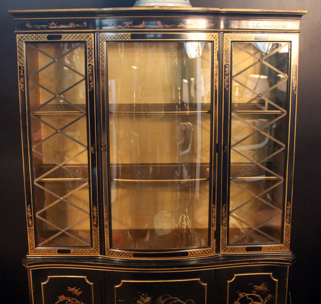 1940s black lacquered with gold decoration breakfront cabinet. Brass fittings and glass detail. Gold interior. Beautiful piece.
Curved glass front. Two shelves with plate grooves. Three lower cabinets with one shelf each.