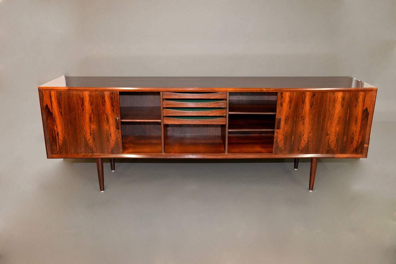 Danish Midcentury tambour credenza with Brazilian Rosewood by Kofod Larsen for Mobelfabrik.  Large case is finished on the back for 360 degree use. Interior features 3 adjustable shelves & four rosewood faced mahogany drawers.  Solid rosewood