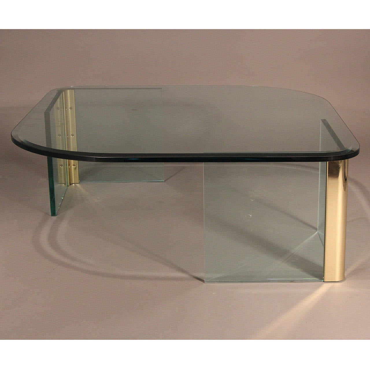 Asymmetrical 3/4 inch heavy glass top table over brass and glass supports.