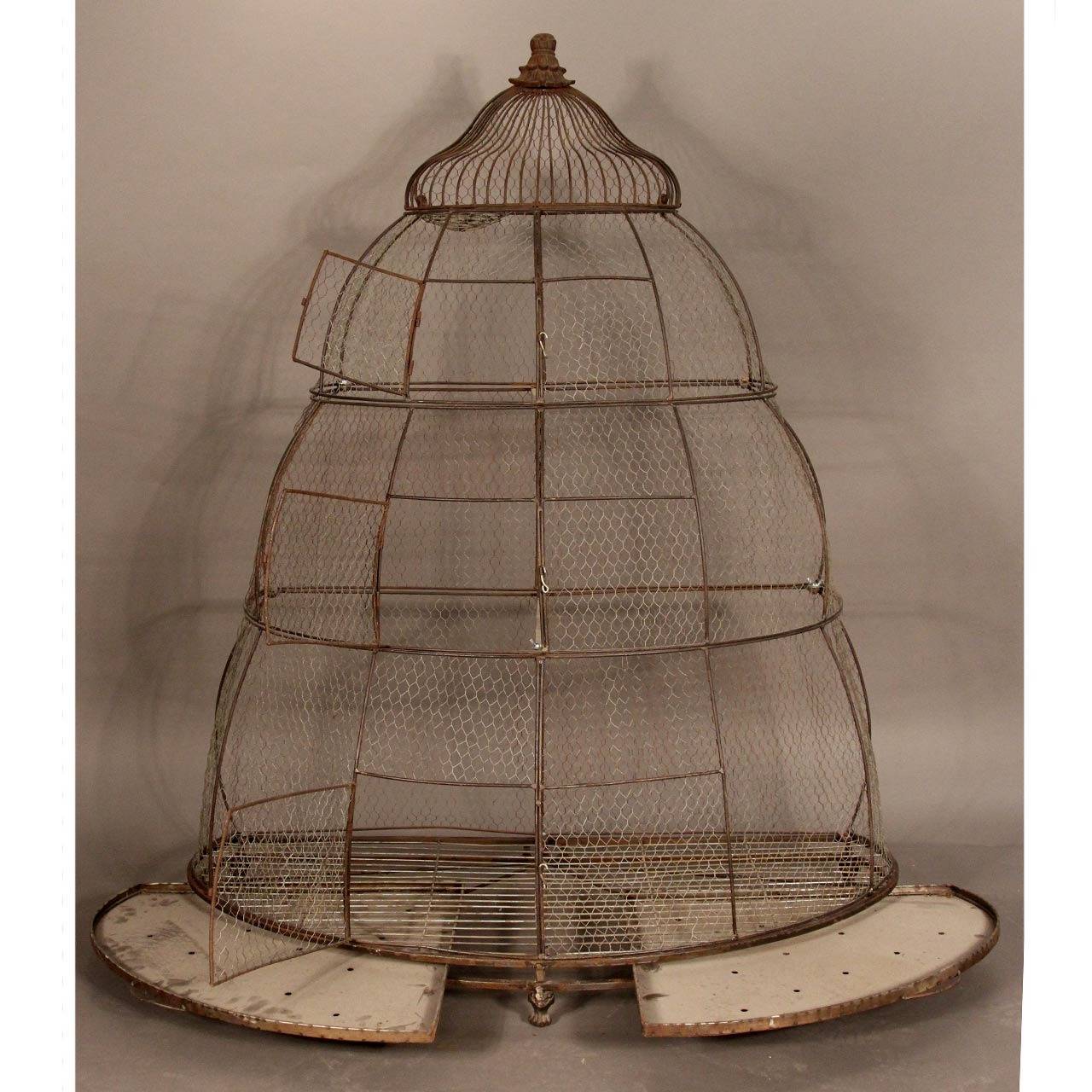 Unusual functional and beautiful architectural style bird aviary/cage. Three working doorways and a wire nest in cupola area for young birds/breeding. Removable slide-out bottom trays. Gorgeous demi-lune shape with floral motif finial and feet.