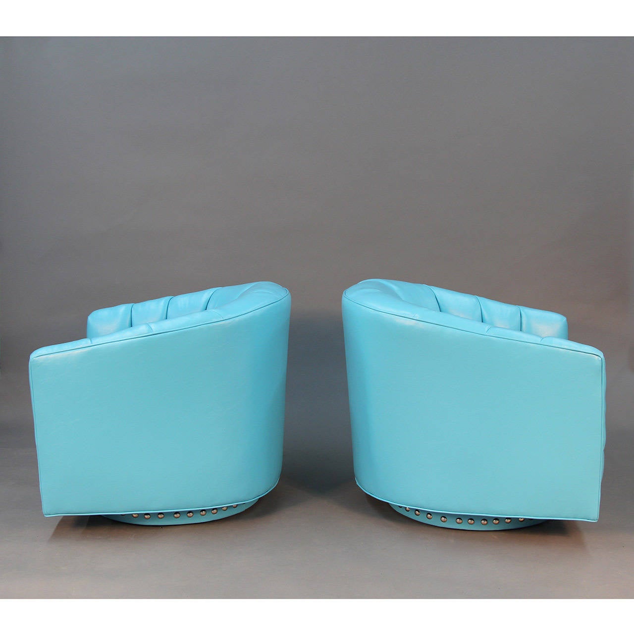 Turquoise swivel lounge chairs.  Channelled back, nickel studded base, waterproof faux leather material.