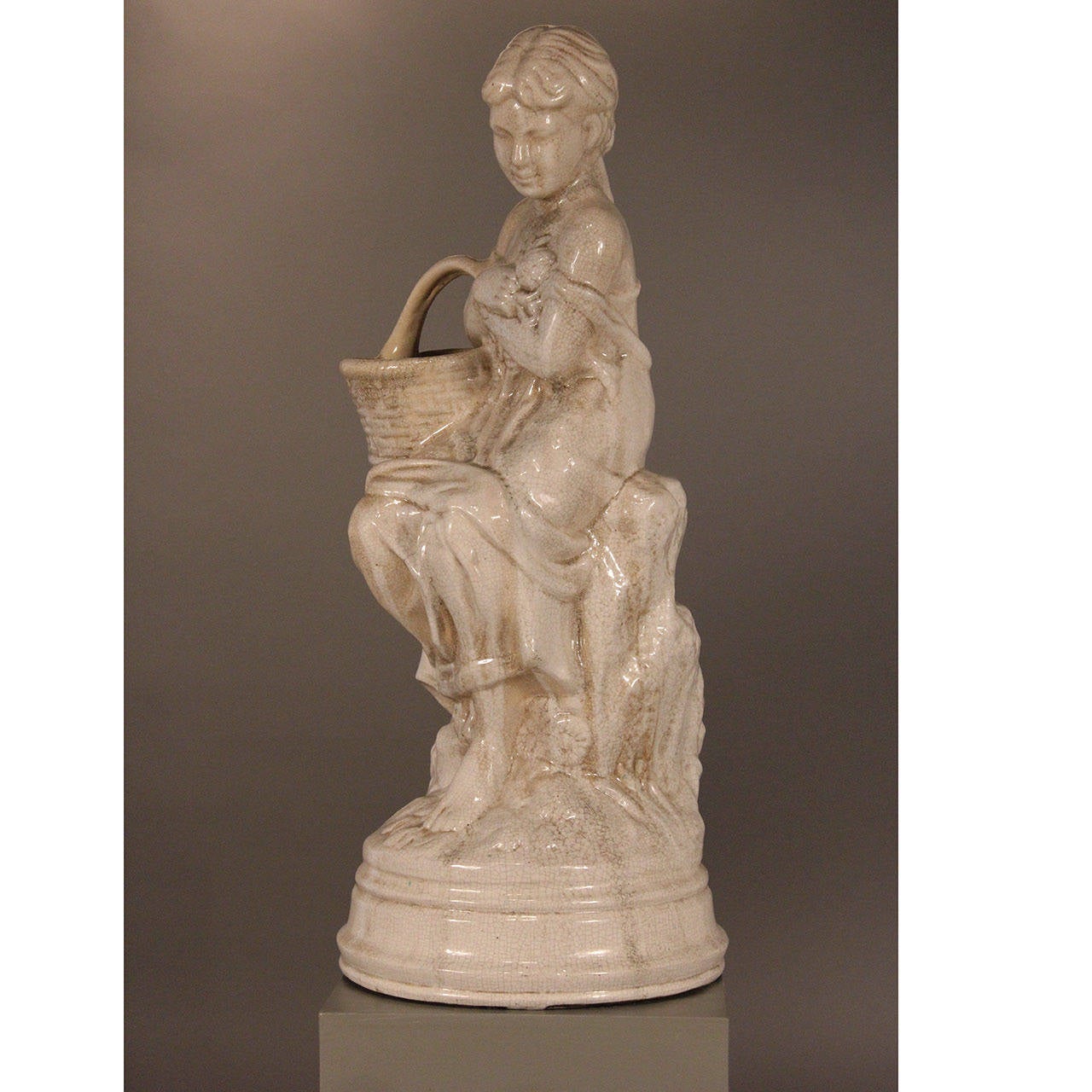 Seated lady holding flower basket. Glazed ceramic Blanc crackleur.