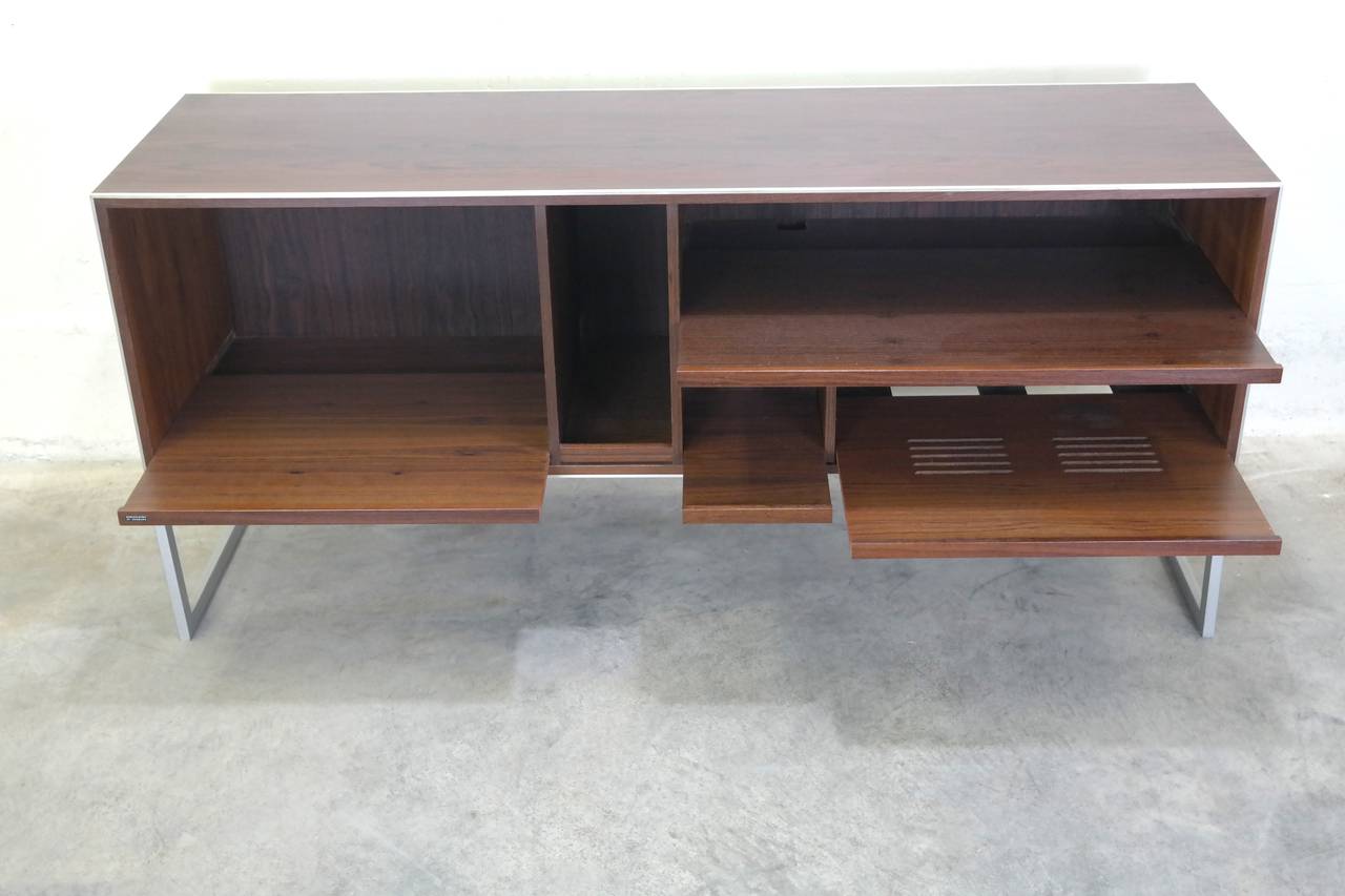 Bang and Olufsen stereo cabinet in rosewood, various compartments for storage, including sliding pull-out shelves for easier access. Trim and legs in aluminium.