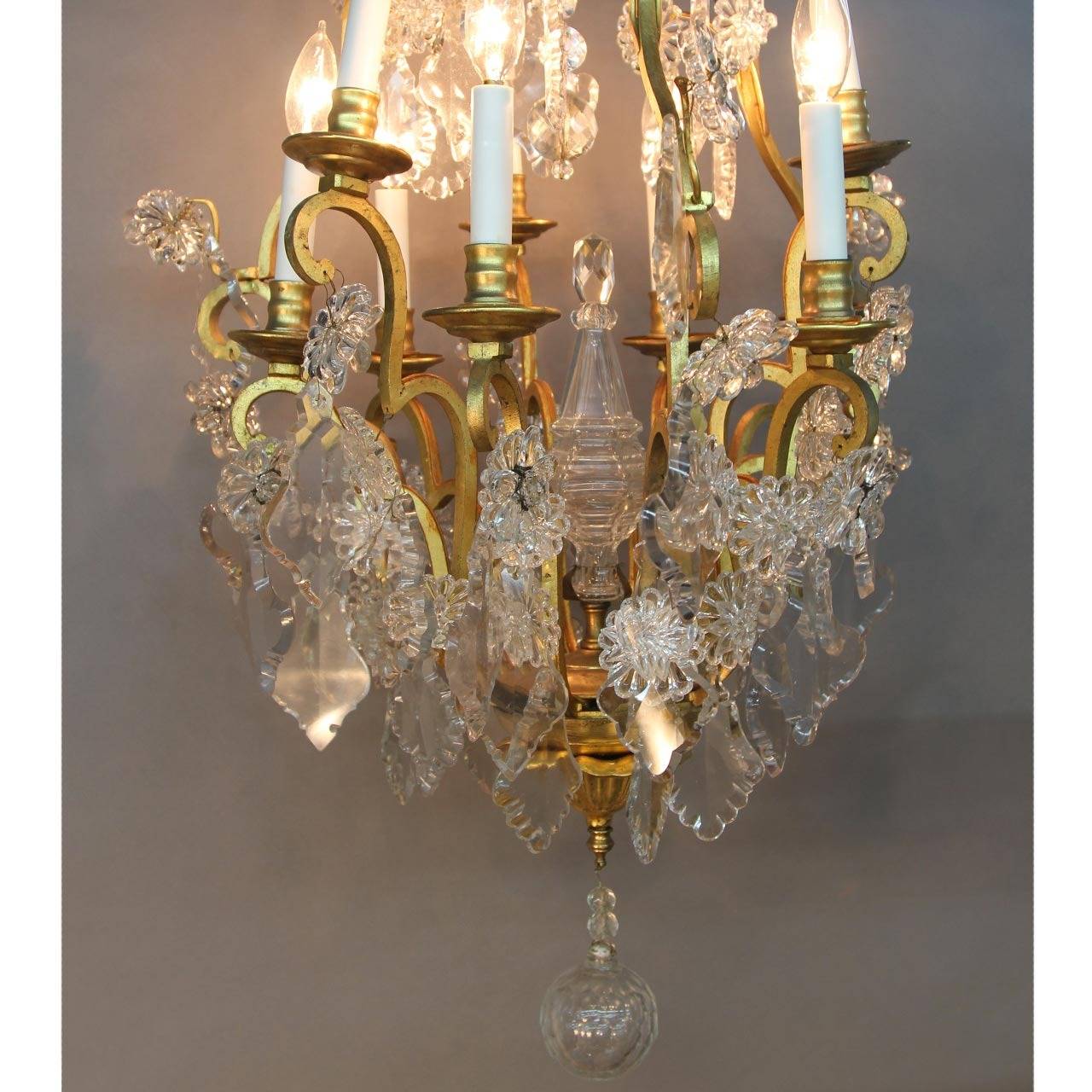 Magnificently appointed French chandelier in the style of Louis XV. The beautiful nine-arm gold gilt bronze chandelier is adorned with beveled and cut ornate crystal stars and crystal flower rosettes. The center column of the chandelier is also