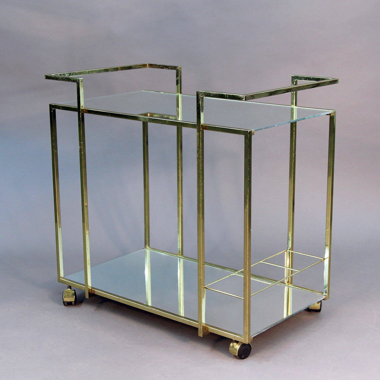 Beautiful brass bar cart with mirrored shelves in modern Hollywood Regency style. Clean lines, with bottle holders and two shelves. Beautiful addition to any Mid-Century or modern decor.
