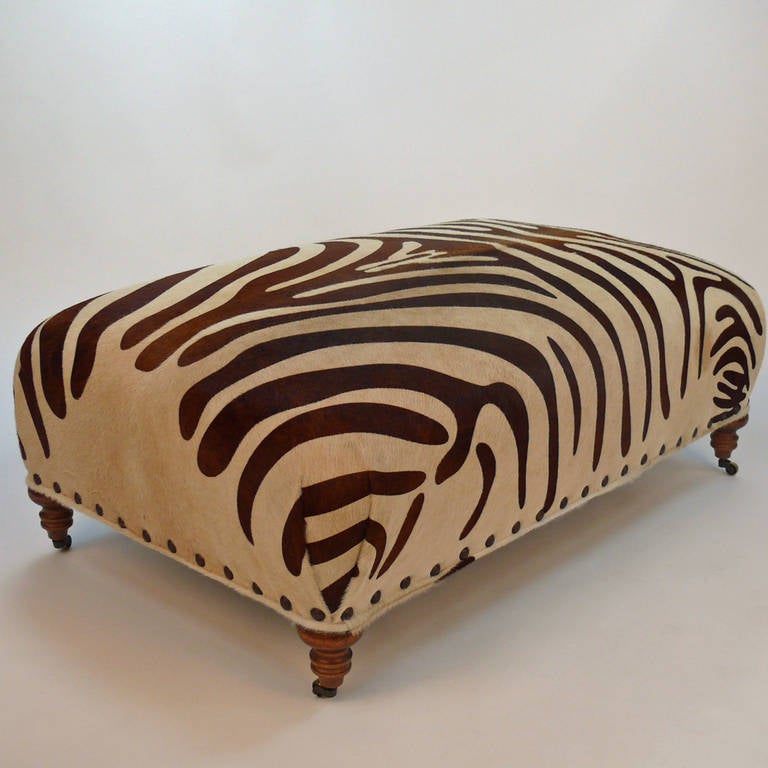 Newly upholstered cow hide in Zebra print ottoman or coffee table.  Turned legs on castors.
