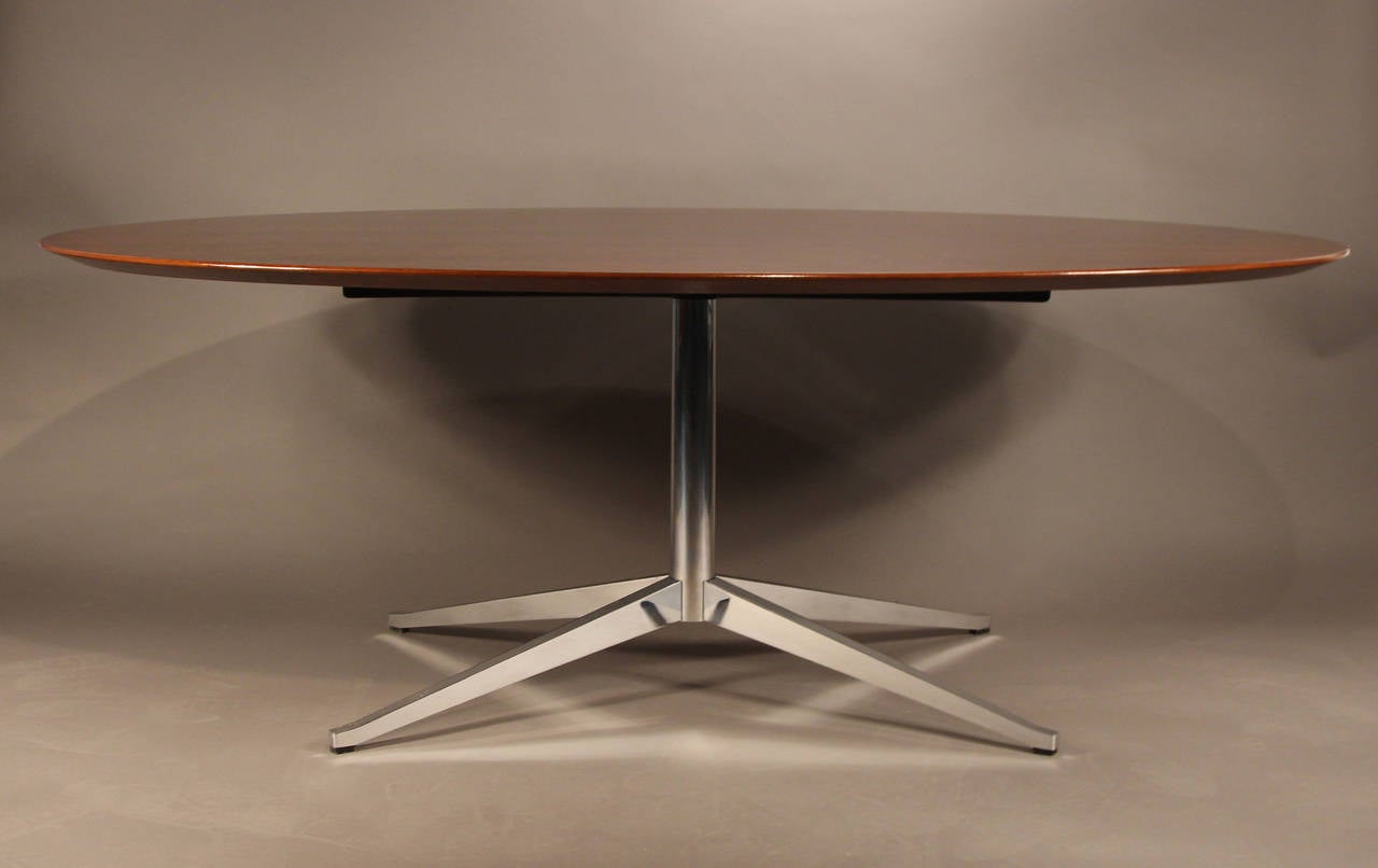 Beautiful newly refinished and lacquered Florence Knoll oval table in rosewood. Designed by Florence Knoll and used as a dining table, conference table, or desk. Gorgeous rosewood sits atop a newly polished chrome base.