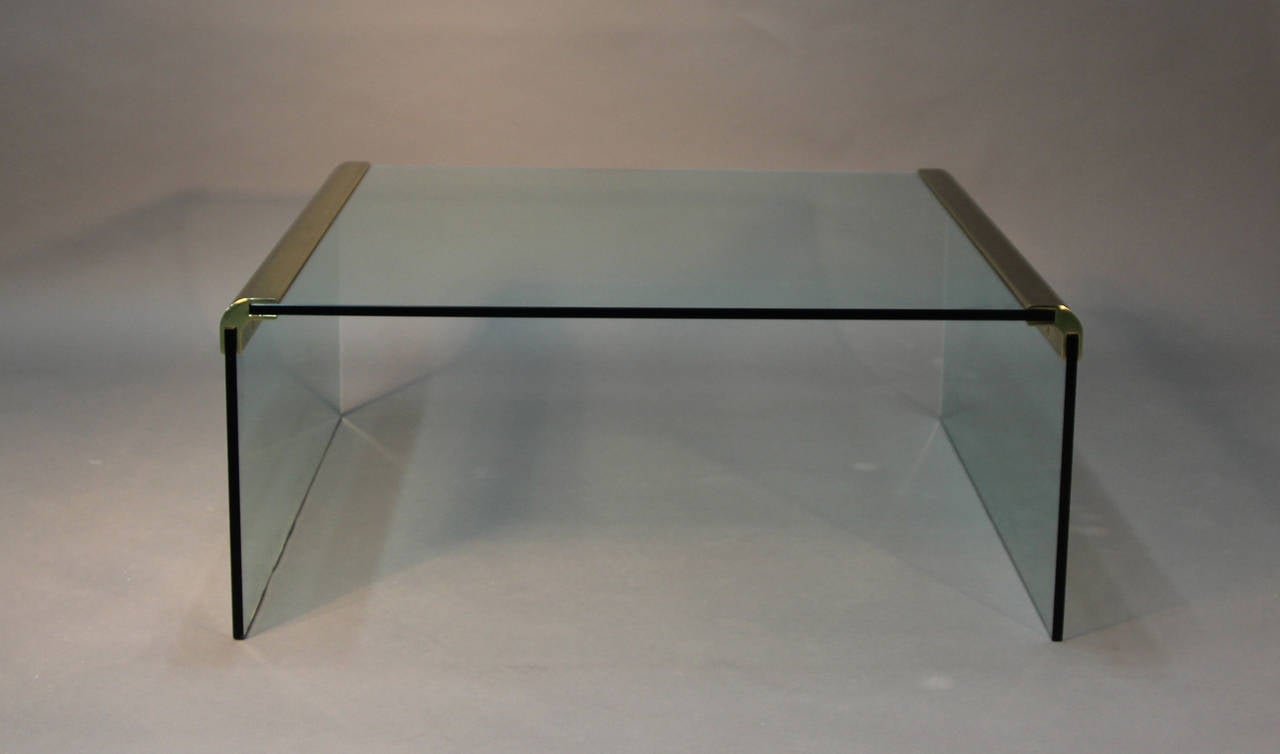 Glass coffee table with solid brass corner accents.