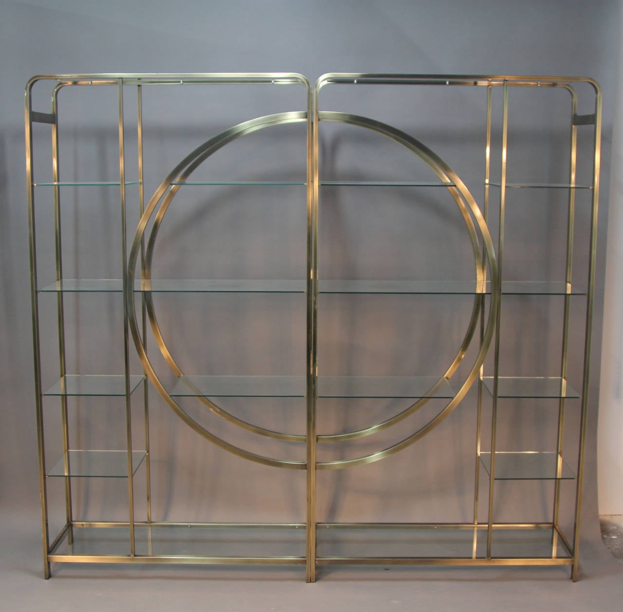 Incredible pair of antiqued brass etagere.  Joined together they create a beautiful circle.  Glass shelves with multi tiered configuration.  Unique and wonderful set.