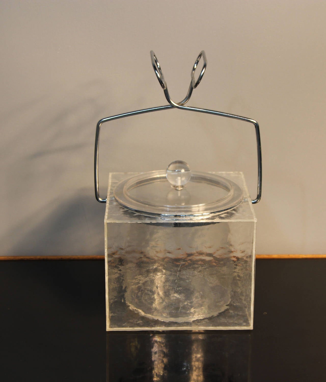 Unique square Lucite ice bucket formed to look like a block of ice with chrome ice tong handles and a round insert. Unsigned.