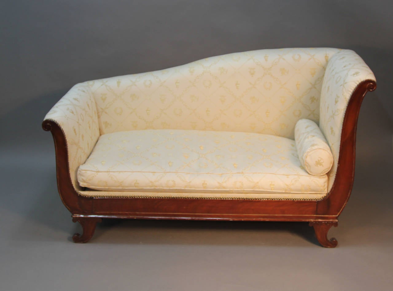 This sexy and sleek French Empire sofa is covered in a netural silk fabric.  The french-polished mahogany veneer frame has scrolled feet and arms imitating a sleigh bed.  The simple lines mix well with modern furniture.  There are a few slight dings