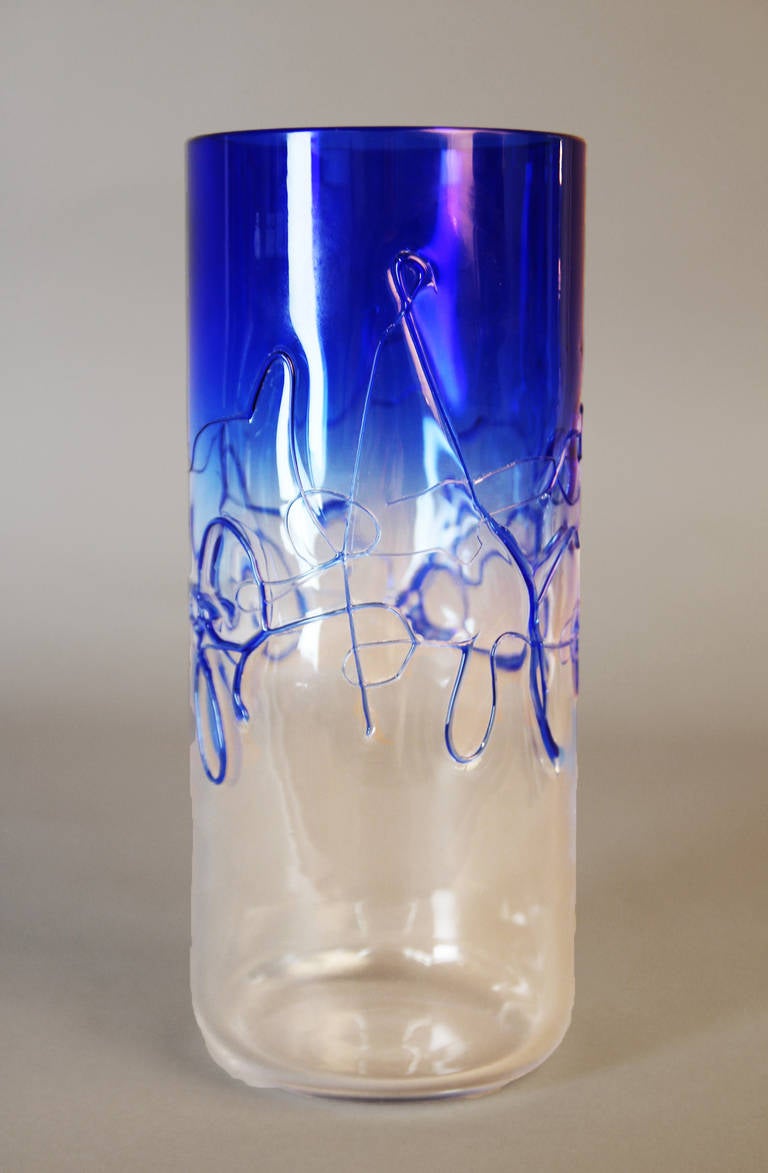 Tall cylindrical Murano glass vase in clear and cobalt blue. This vase has a gradation of color from clear to intense blue midway around the circumference of the vase under the threaded glass abstract design. Signed Barbini Murano.