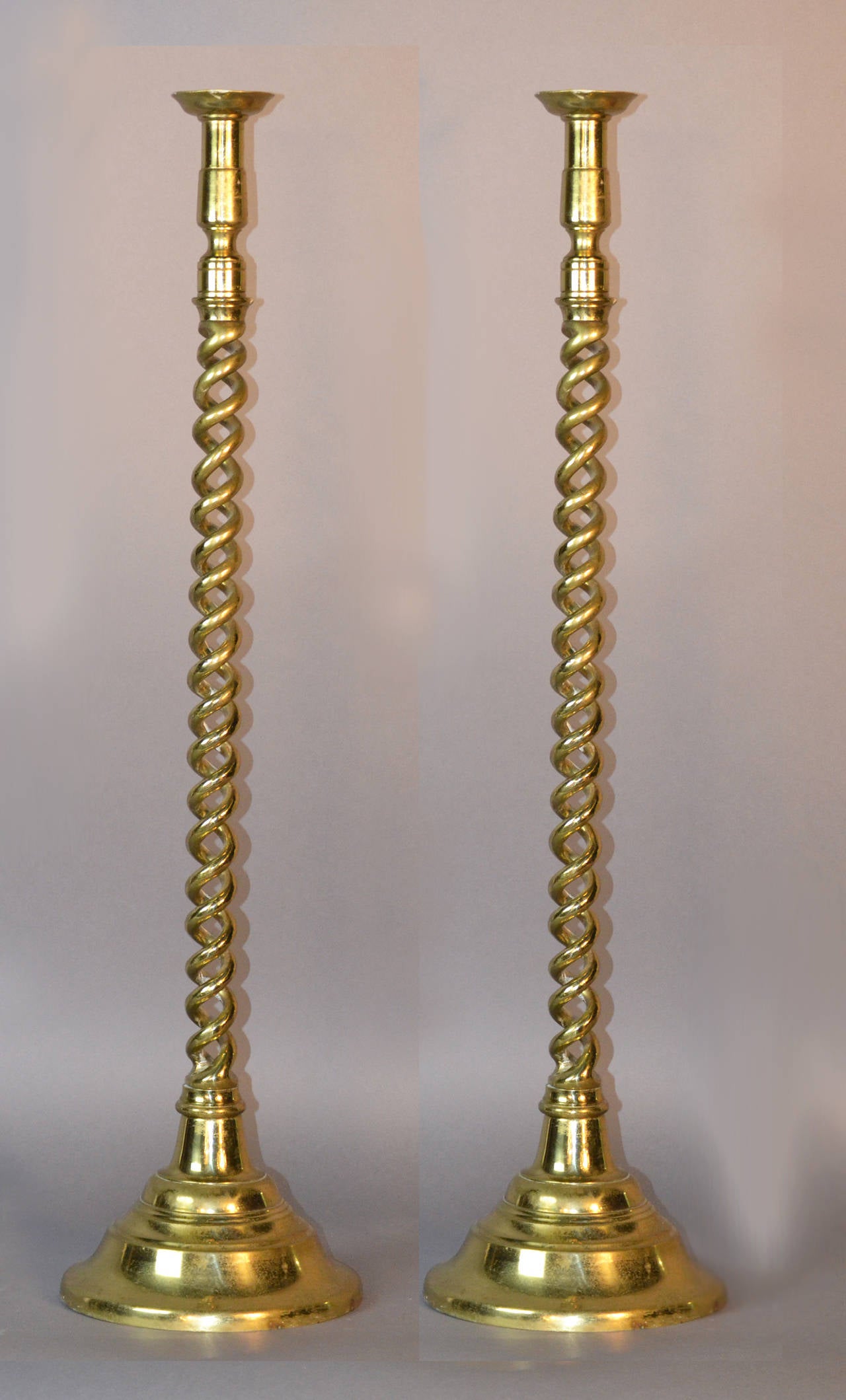 Pair of tall English floor candlesticks in barley twist design on circular bases.