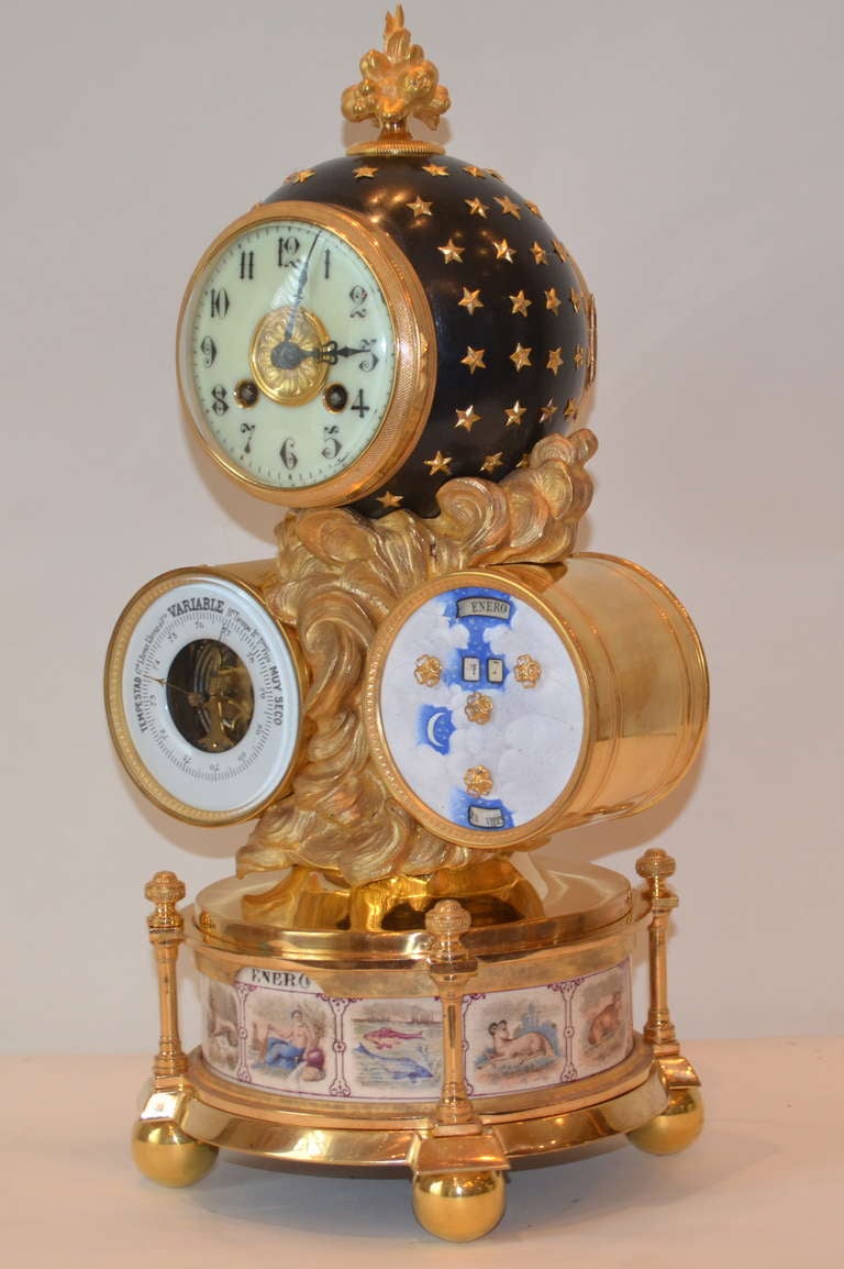 A rare and unusual Spanish desk clock the case in gilded brass and gilded bronze. The circular base rests on four ball feet and contains a rotating hand painted drum showing the signs of the zodiac; the base supports gilded clouds holding three