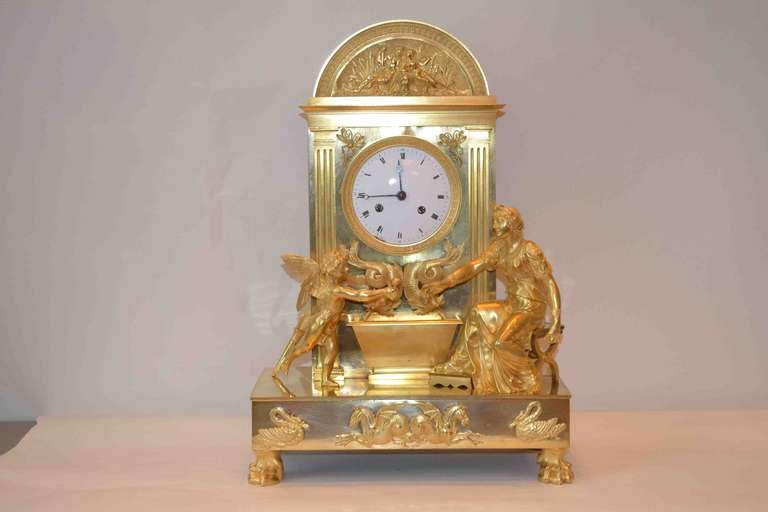 A first quality period French Empire mantle clock in original fire gilded case;  two figures, a standing winged cupid, and a seated classically draped maiden are either side of a fountain fed by two dolphins; the figures are on a rectangular base