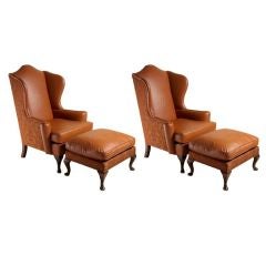 Pair of carmel leather wing chairs and ottomans