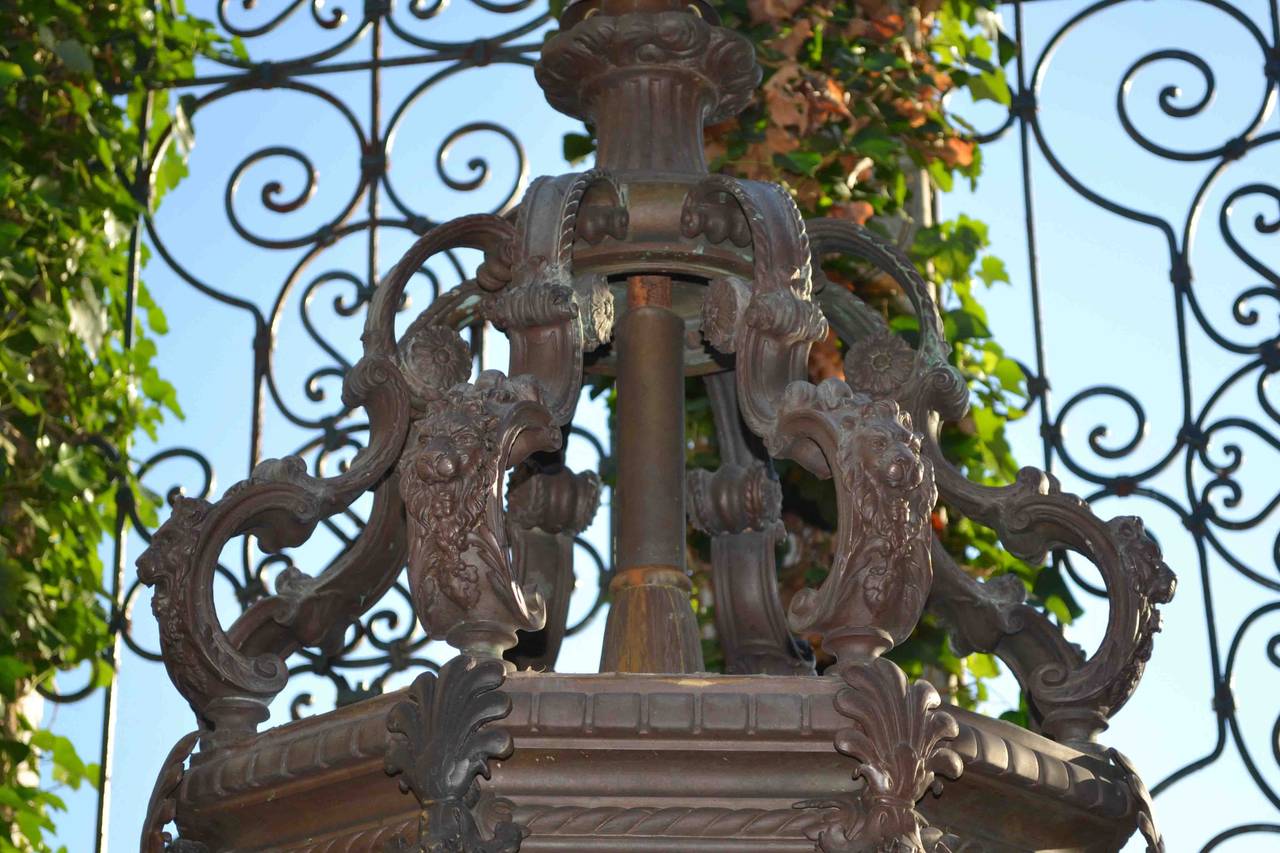 Monumental bronze and frosted glass lantern; likely Italian early 20C; reportedly at one time hung in an important public building in downtown San Francisco; the main body of the lantern is suspended from eight scroll arms featuring well cast lion’s