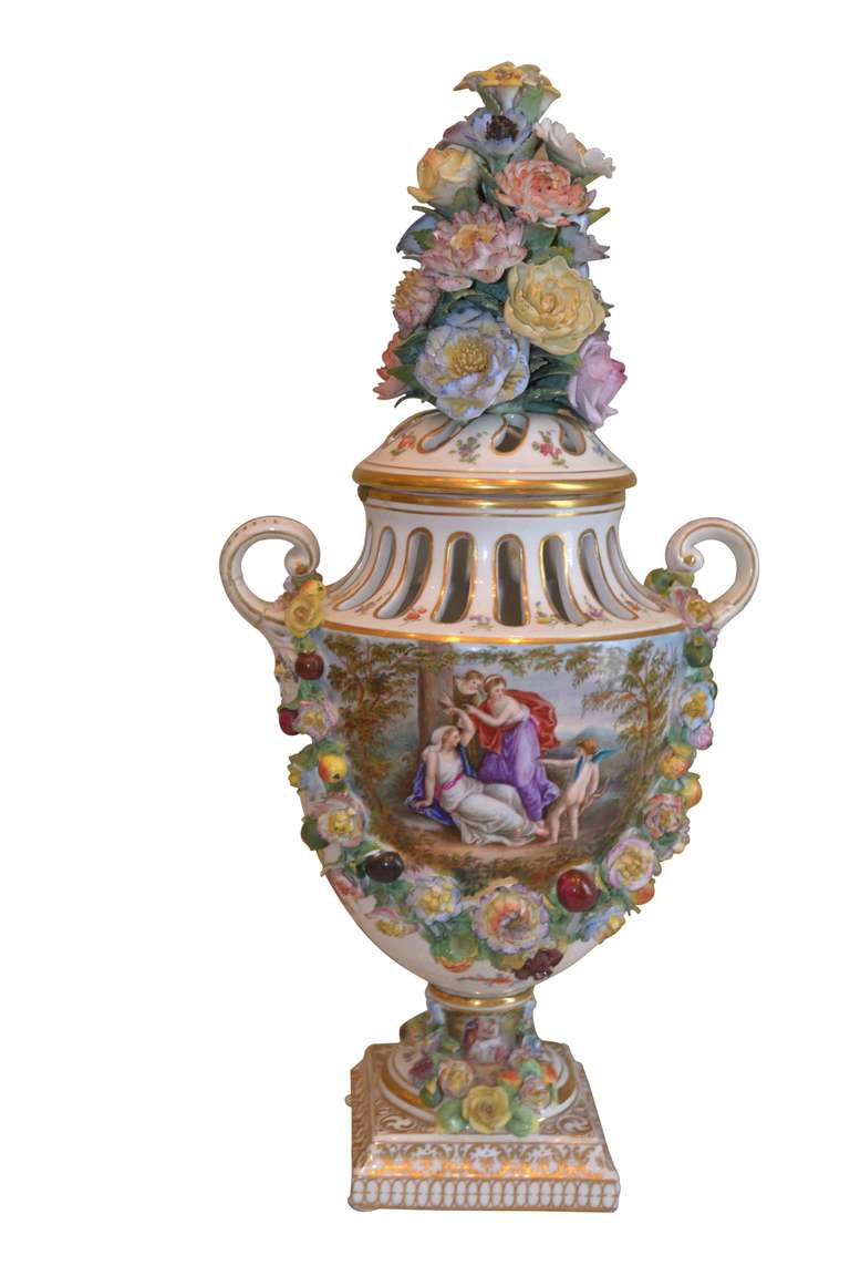An exceptionally well modeled and painted mid to late 19thC lidded urn signed by the Dresden factory in Germany, with all over applied flowers to the ovoid body of the urn, the base and to the tall lid.  The front of the urn features a classical