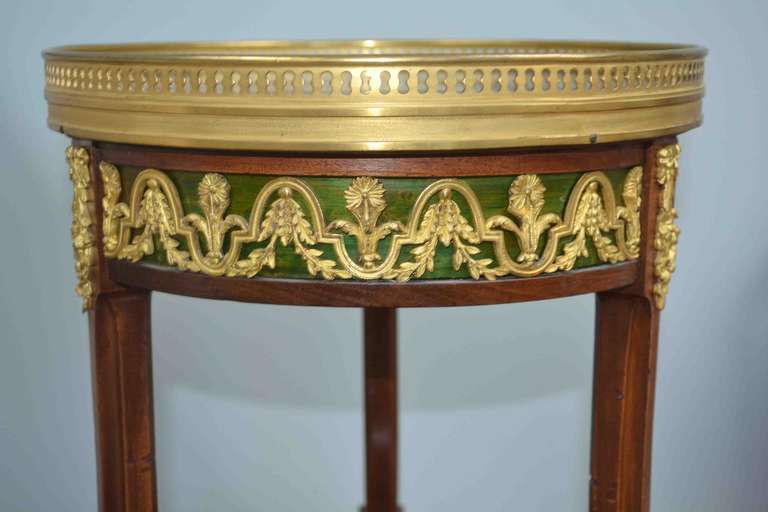 A fine quality occasional table the top section having a blue/gray galleried marble top; below the top is a fine quality ormolu band backed on green stained wood; joined to the middle section by three curved inlaid supports; the larger middle tier