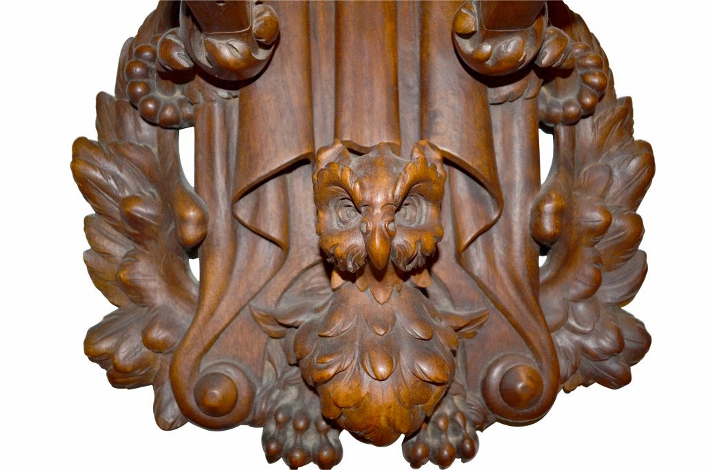 A large pair of carved walnut wall racks, (possibly for rifles), one having a rooster's head at the base, the other appearing to be an owl's head; one signed Maurice Michon.