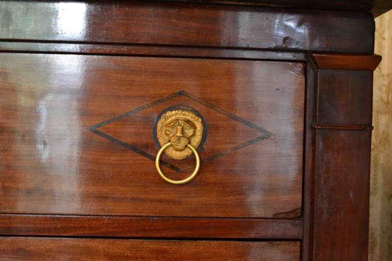 A classic early French Empire semainier in mahogany; each of the seven drawers (one for each day of the week), has ebony inlay around each of the gilded lion's mask door pulls, and a fine gilded escutcheon around the key hole; the chest has it's