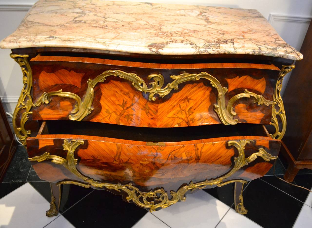 A wonderful quality Louis XV style two-drawer bombe chest in the manner of Pierre Migeon (1733-1775); the oak carcass with overall kingwood and rosewood parquetry; the front central lozenge decorated with inlaid Chinese figures, birds, trees etc.