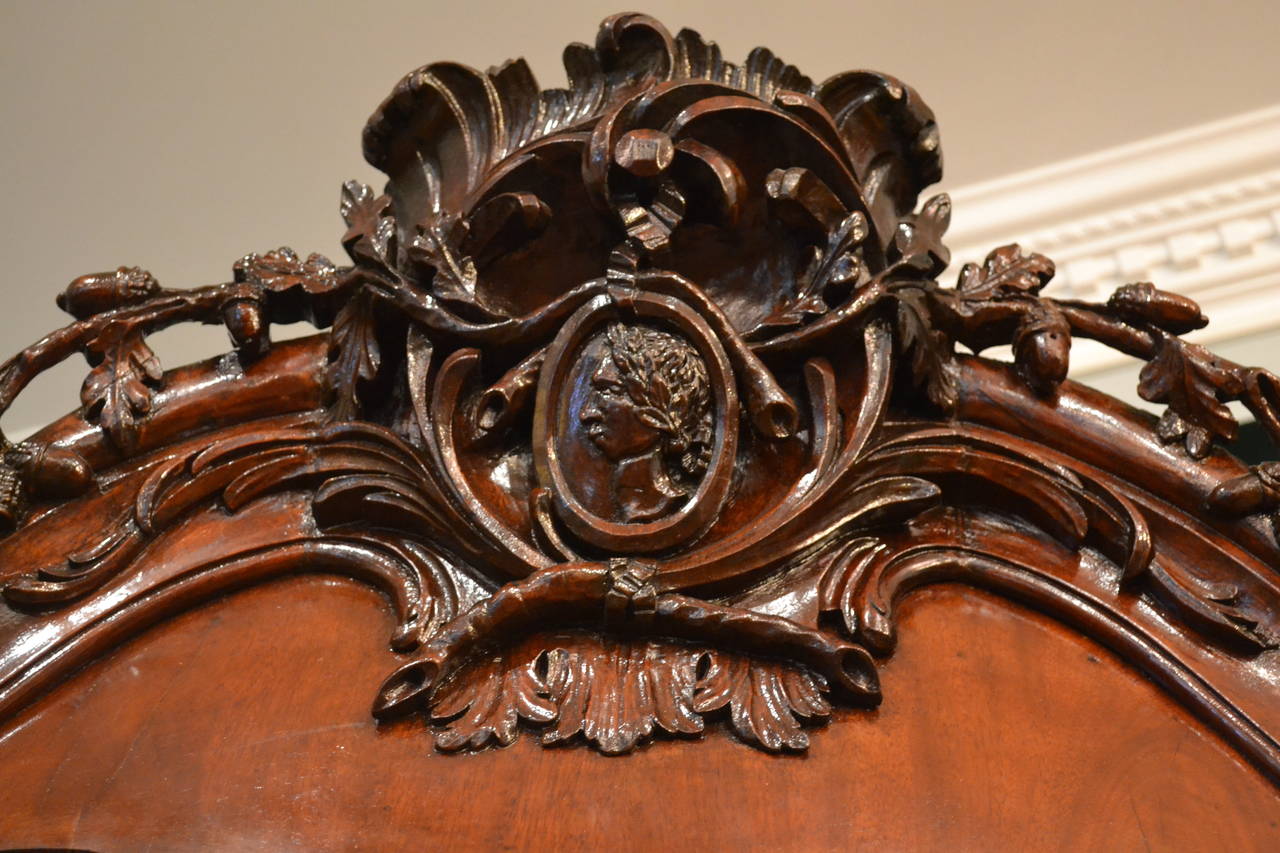 A large and very impressive 18thC Dutch armoire in beautifully figured mahogany.  The top pediment with a central cartouche carved with the profile of a classical man (repeated on the top of the top front doors), is also carved with acorns and