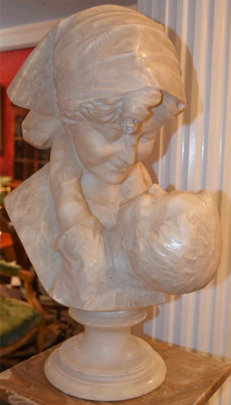 A wonderful 'Romantic' representation of a young child smiling up at his mother with his arms around her neck, her kerchiefted head gazing down at him, the whole on a round pedestal base; cleaned and with restorations to the baby's neck; unsigned;