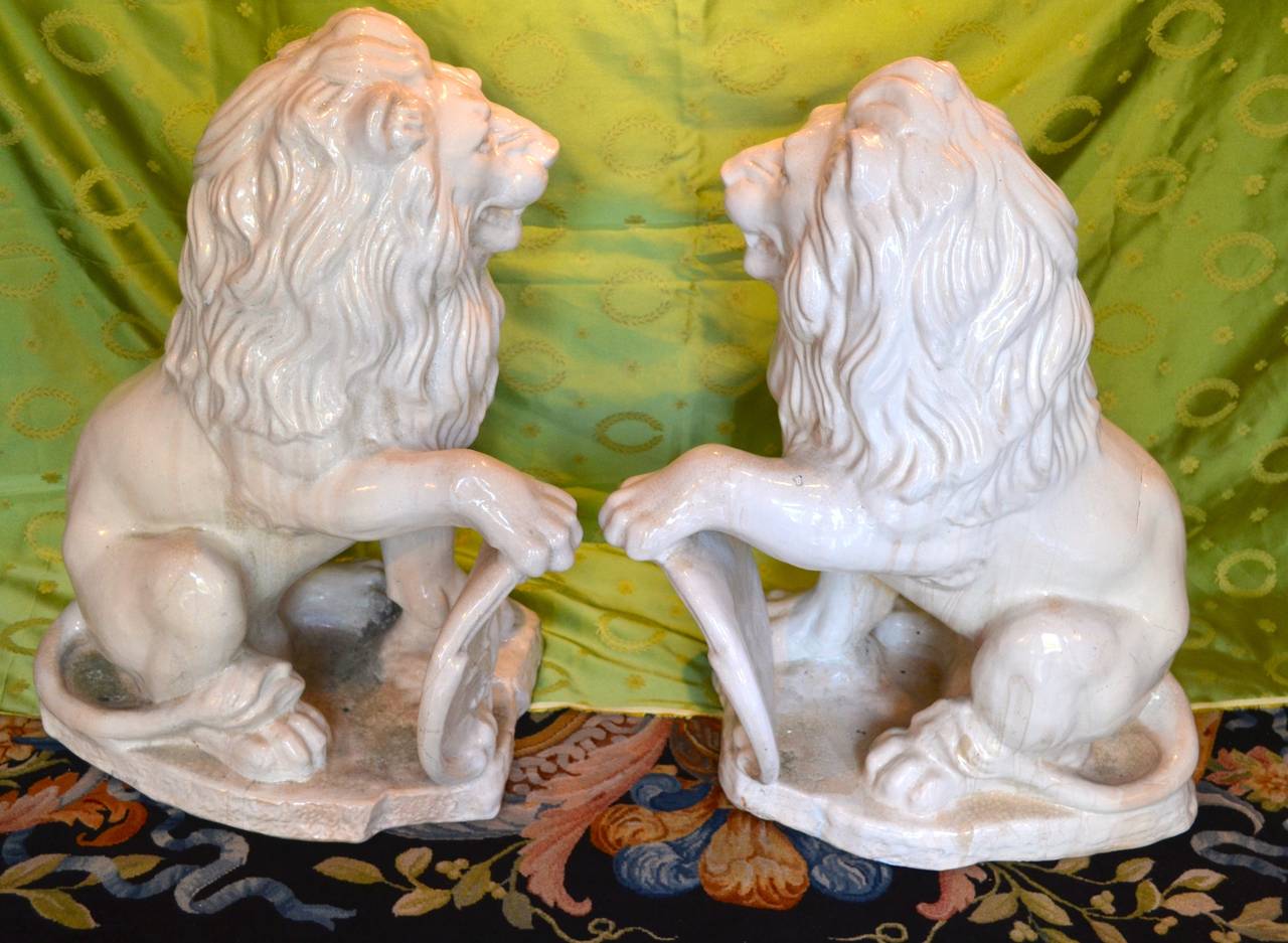 A matched pair of terracotta lions modelled in the Baroque manner, fired with a glazed white finish.  Each lion holds one paw on a 'heraldic' shield featuring a flour de lis.  The large size appropriate for most gardens or foyers.
A pair of large