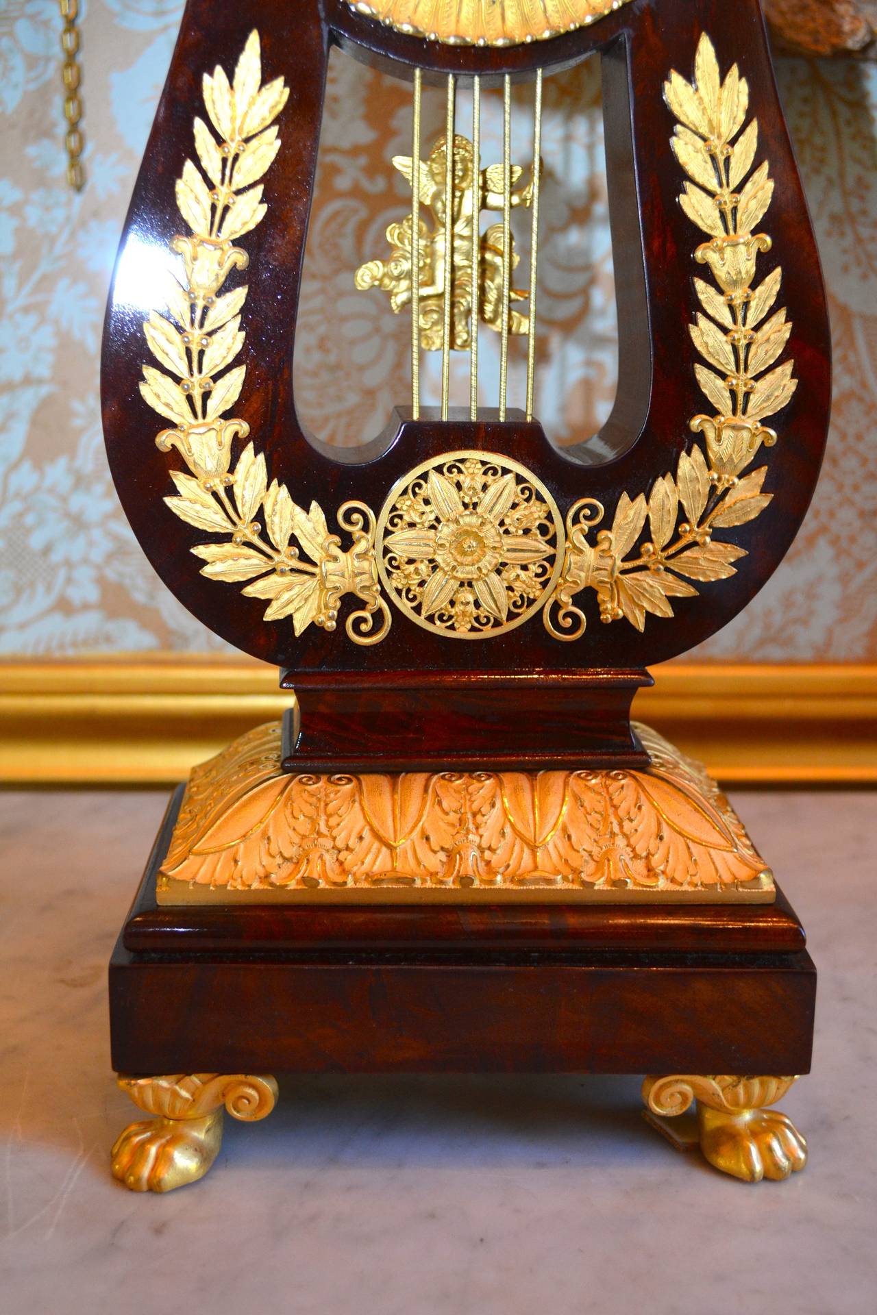 A very fine quality French Restauration period mantel clock in the shape of a lyre; the case in well figured Honduras mahogany richly inlaid with finely chased gilded bronze mounts having the original mercury gilding. The pendulum bob in the shape