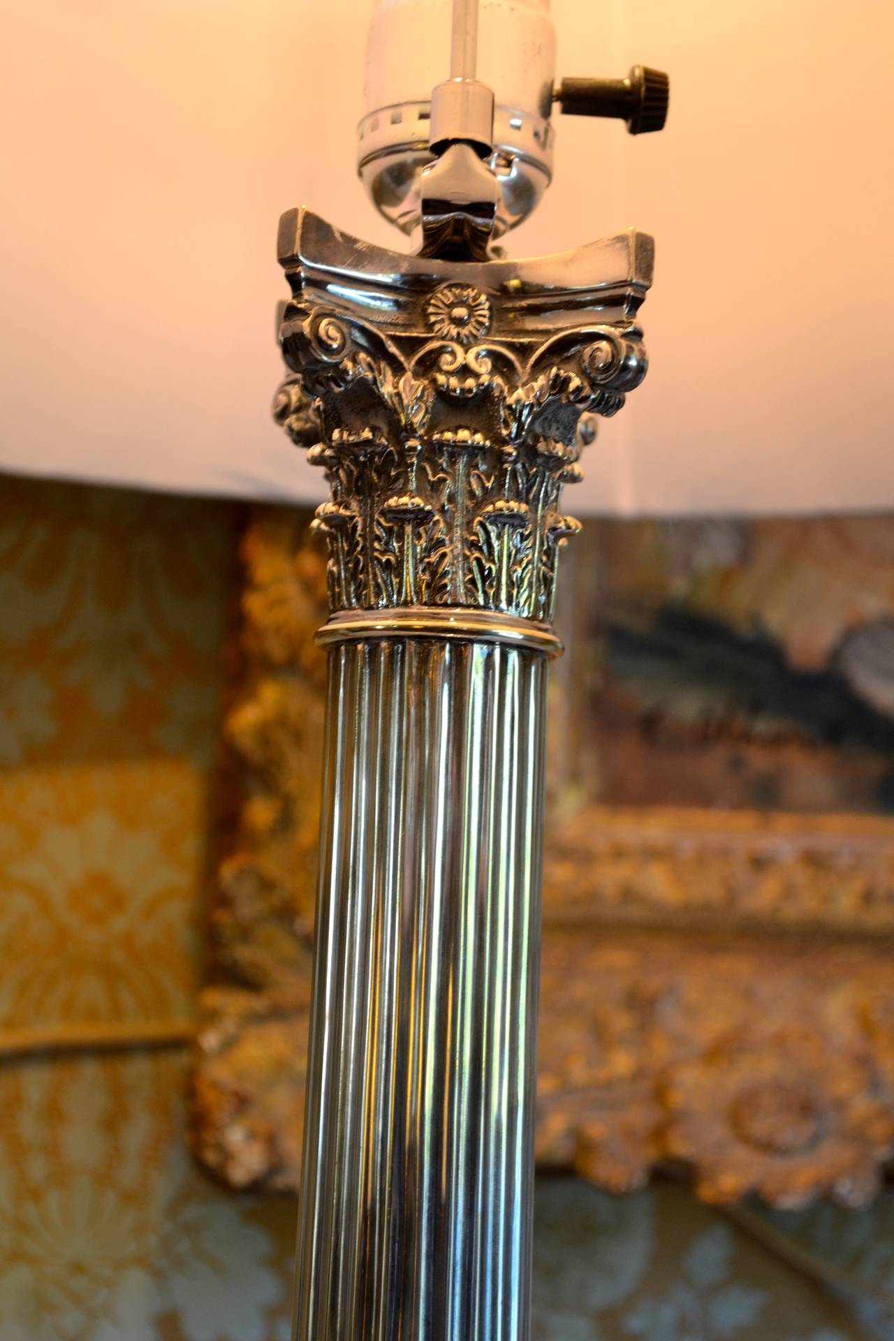 An Edwardian? Sheffield? silver plated classically styled table lamp. the column resting on a stepped rectangular base, the column topped with a Corinthian capital; recently re-wired; together with a pleated light green silk shade. (measurement