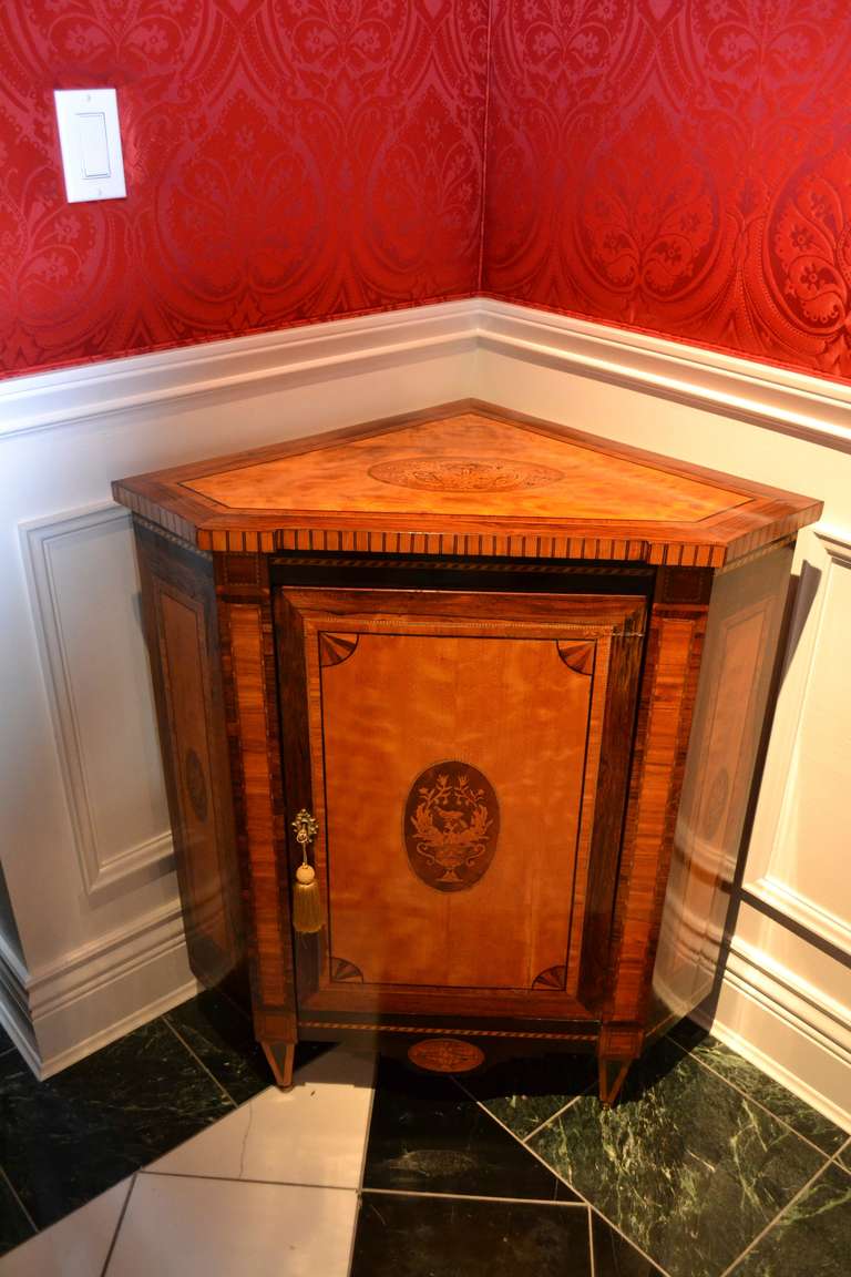 A fine matched pair of late 18th Dutch neoclassical corner cupboards; the oak carcass veneered primarily in satinwood and rosewood, with various exotic woods forming the banding and inlaid decoration; the top and front door, (one oak shelf in the