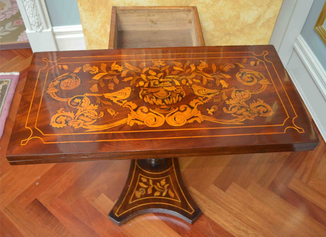 A beautifully inlaid Dutch mahogany games table of the early to mid 19th century as noted in the photos the swivel top opens to reveal a round baize lined gaming surface with the four mahogany corners inlaid with playing cards. The depth dimension