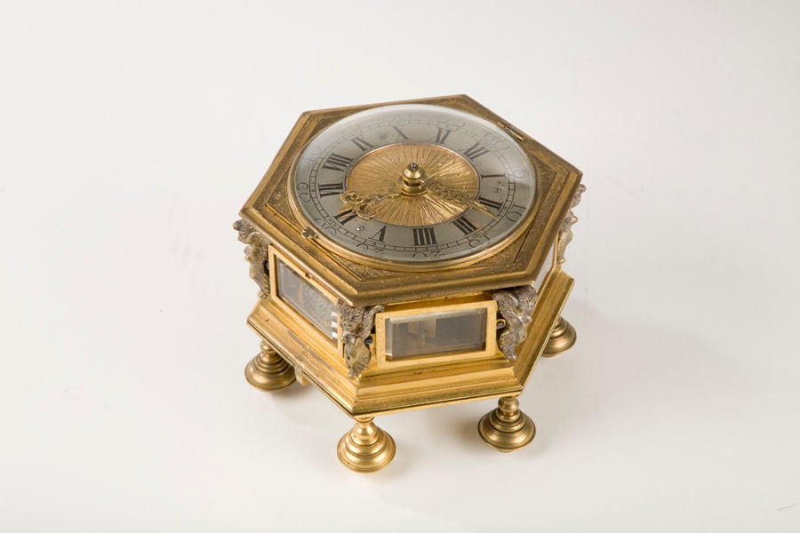 A late 17thC six sided table clock with alarm in gilded bronze case with crystal side panels. The hinged bottom plate opening to reveal the movement, (the bell is located in the bottom section). The going train with fusee and chain for the verge