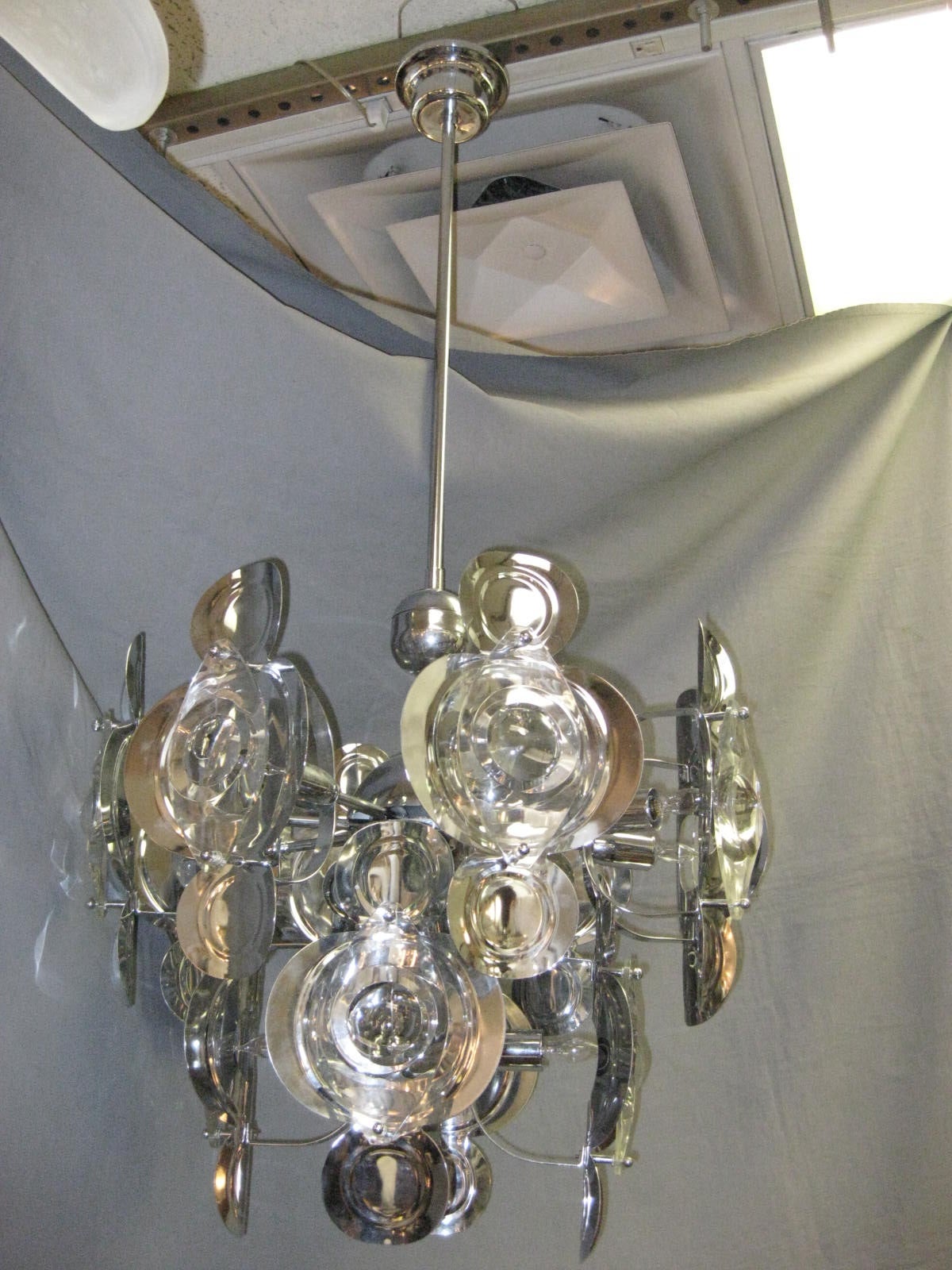 Italian, Mid-Century Modern Gaetano Sciolari two-tier chandelier featuring a Sputnik frame and stepped canopy in the original chrome finish. Large optic glass lenses are decoratively and functionally mounted on unusually shaped concave metal shields