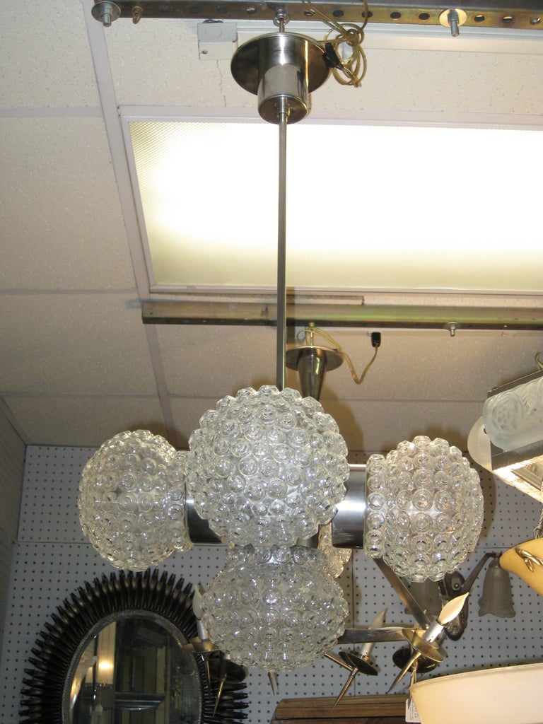 Mid century Modernist Italian ball chandelier. Five glass spheres with overall globule pattern delicately suspend from a polished nickeled bronze tubular stem and cylindrical canopy.
Newly wired for American specs. Each globe unscrews to reveal one