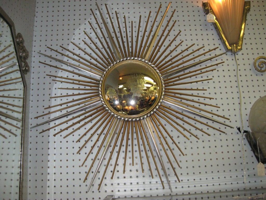 French authentic Modernist sunburst mirror attrib to Chaty Vallauris . Gilt and silver rays of varied lengths and widths adorn this soleil mirror. The original central convex mirrored inset is surrounded by a silver braided detail.
Key words: Art