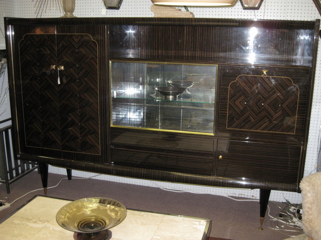 French asymmetrical cabinet with vitrine, bar, two drawers and open shelving decorated with mother of pearl inlay, gilt accents and raised on tall legs with sabots. The interiors of the compartments are refinished in beautiful ribbon stripe mahogany