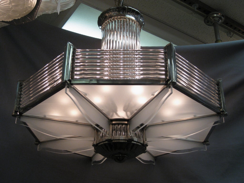 French octagonal shaped Modernist Petitot chandelier. Highly polished nickeled bronze armature holding horizontal glass rods, flat frosted glass insets and frosted and polished winged panels. The top bearing an illuminated glass rod stem with