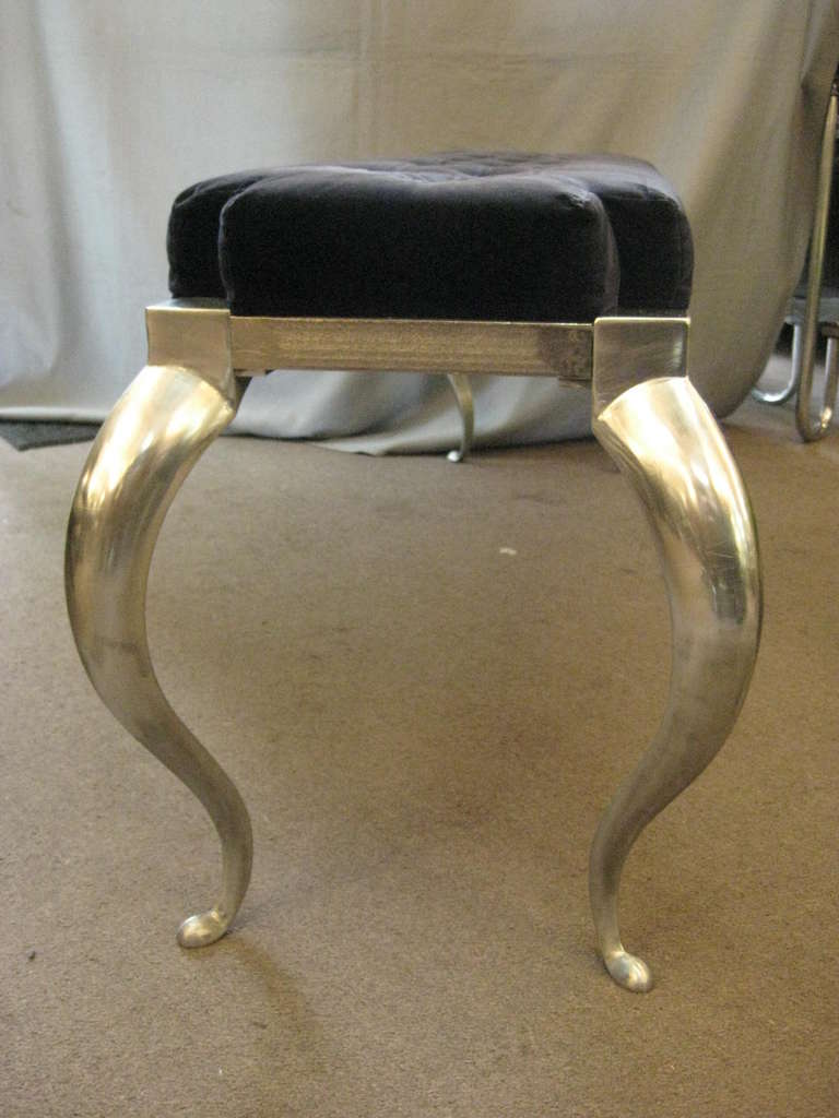 A fine French Art Deco long bench attributed to Rene Prou. Four elegant tapered, cabriole legs hold a linear frame support and a tufted navy blue velour upholstered seat. Polished aluminum legs with nickeled forged iron surround.
Two available;