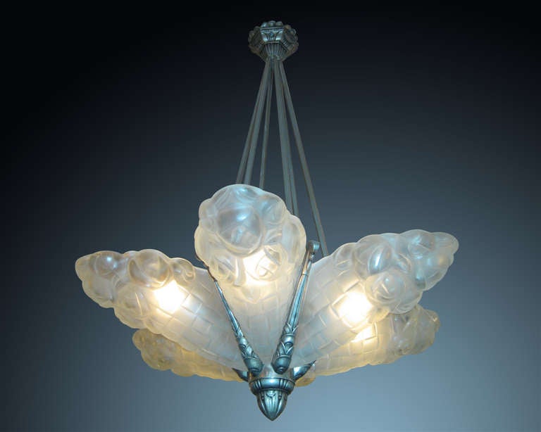 French original Art Deco up lit chandelier with 6 Degue signed molded frosted glass panels in a stylized floral cornucopia motif. The panels jut outward in a sunburst pattern from their original satin nickel plated six rod highly decorative bronze