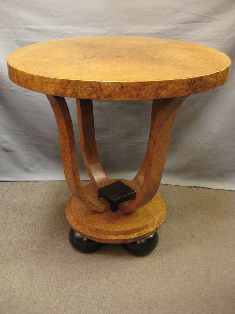 An unusual pair of French Art Deco side tables in amboyna with dark brown walnut accents. The delicate and graceful tulip shaped base is raised on circular steps ending in ball feet. This four legged curved base is most favored among collectors and