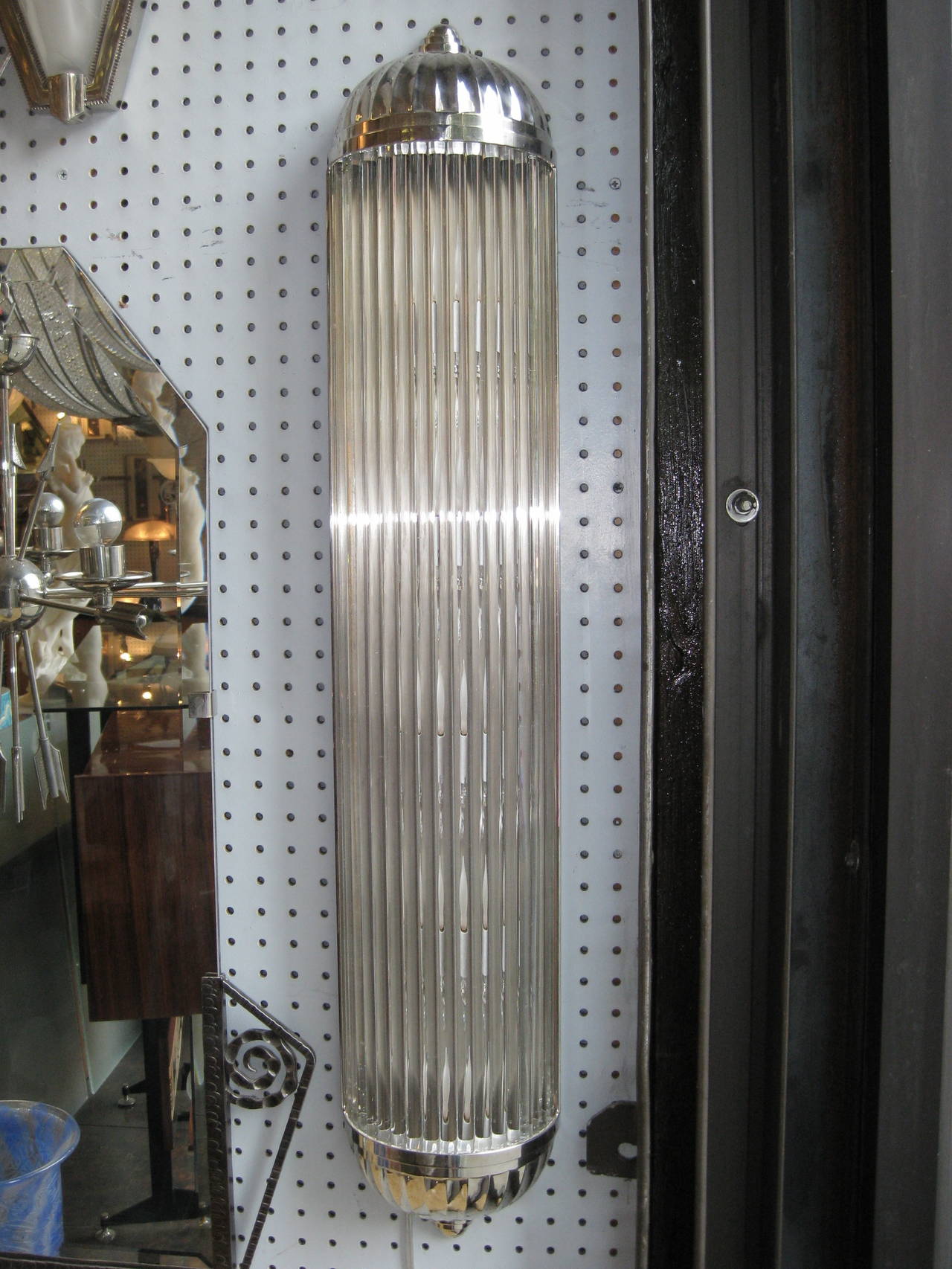 French tubular sconces featuring long solid glass rods that form a semi cylindrically shaped column, mounted in heavily cast polished nickeled bronze frames with ends terminating in fluted bullet tips.
Sconces can be adapted to hang either