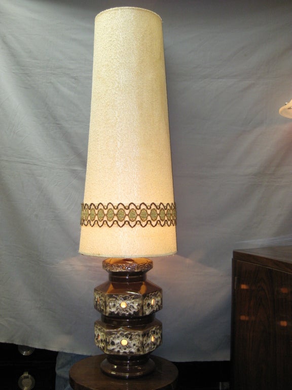 French Mid century tall earthenware lamp. Original brown and white glaze with floral pattern and openwork cutouts for interior light source topped by original tapered shade.
Can be used as a floor or a table lamp. The shade is fabric with a hand
