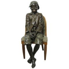 Lifesize Goldscheider polychrome figure of a black boy seated