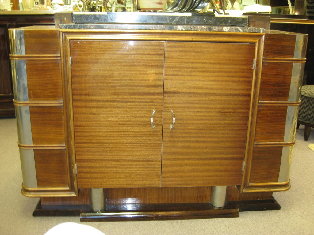 French Modernist ribbon stripe mahogany buffet, circa 1930. Unusual polished nickeled bronze mounts accent the rounded corners of this cabinet with an armour like protection. The horizontal grain echoed by the horizontal molded banding visually