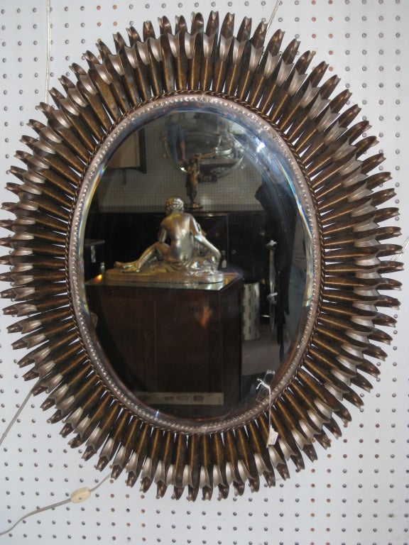 Original French two tone double tiered sunburst mirror with curled eyelash edges in patinated metal and silver leaf.
The satin finish is a beautiful combination of copper, gold and a warm brown color. The interior inset with a fine oval shaped