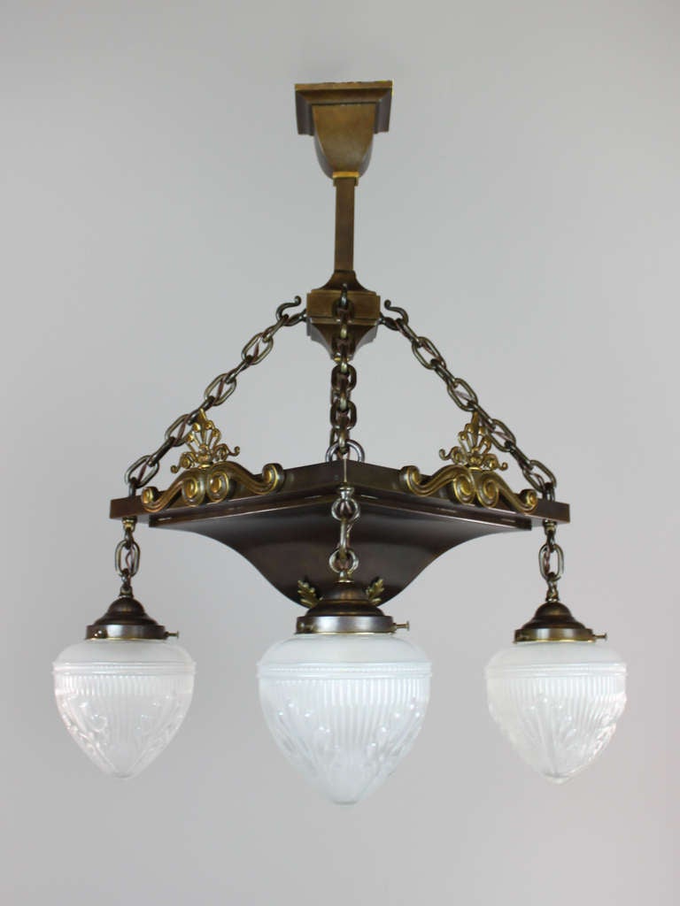 Ca. 1915 Antique Arts & Crafts light fixture with Edwardian-style decorative castings. The square body is suspended by 4 chain lengths which continue to the bell holders fitted with antique acid-etched bullet shades. Re-wired, restored and ready to