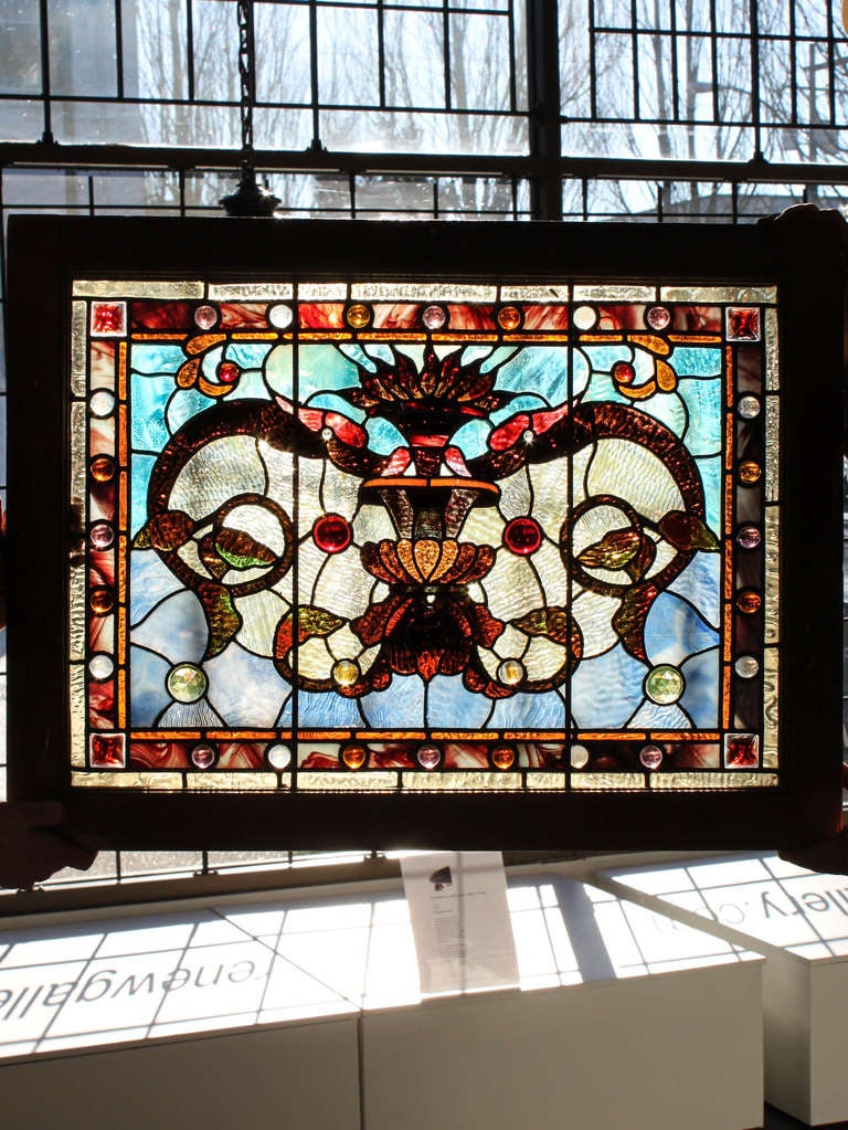 Ca. 1890 A compact window fully decorated in an organic theme of shaded crimson foliate on a cobalt and aqua back-drop. Embellished with prismatic jewels, this window displays all the attributes of an original Tiffany Studios piece. 24