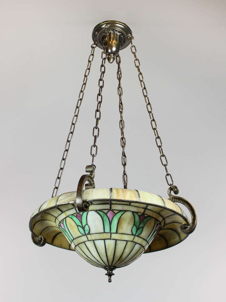 A rare reverse slump glass bowl fixture by famed studio Duffner & Kimberly of New York, circa 1915. Decorated with a lovely floral motif suspended by curled metalwork and chain link off a matched canopy.
Measurements: 19″ W x 36″ L.
 